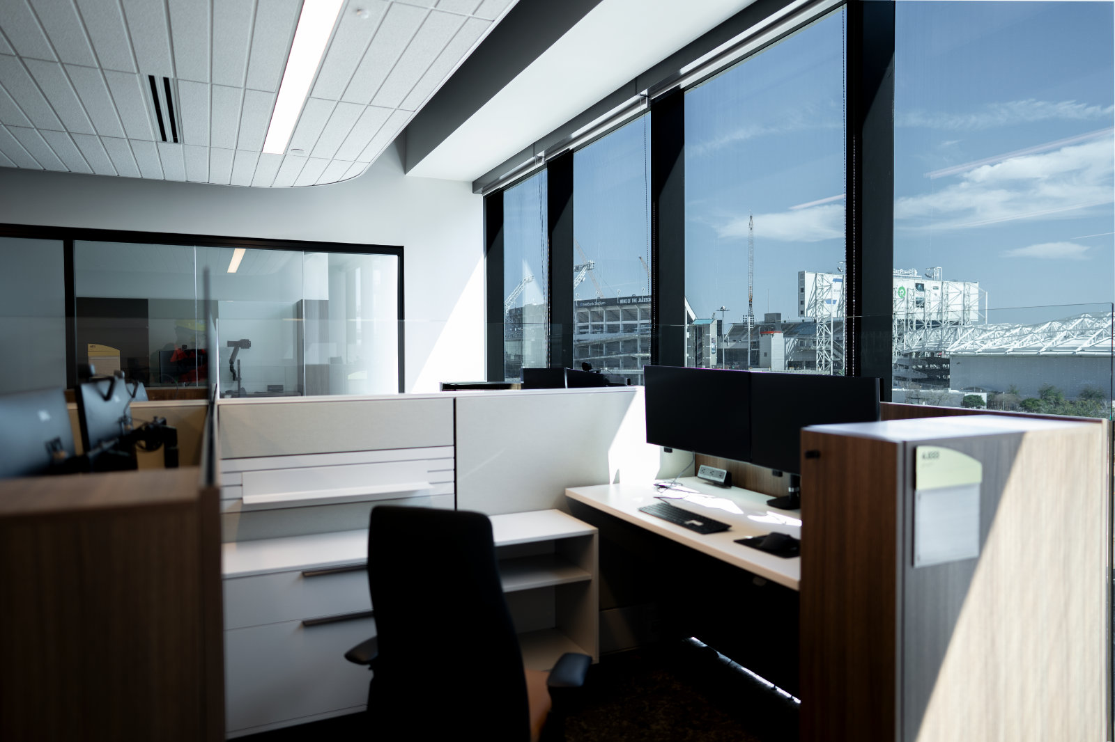 Cubical office space overlooks city through full height windows.
