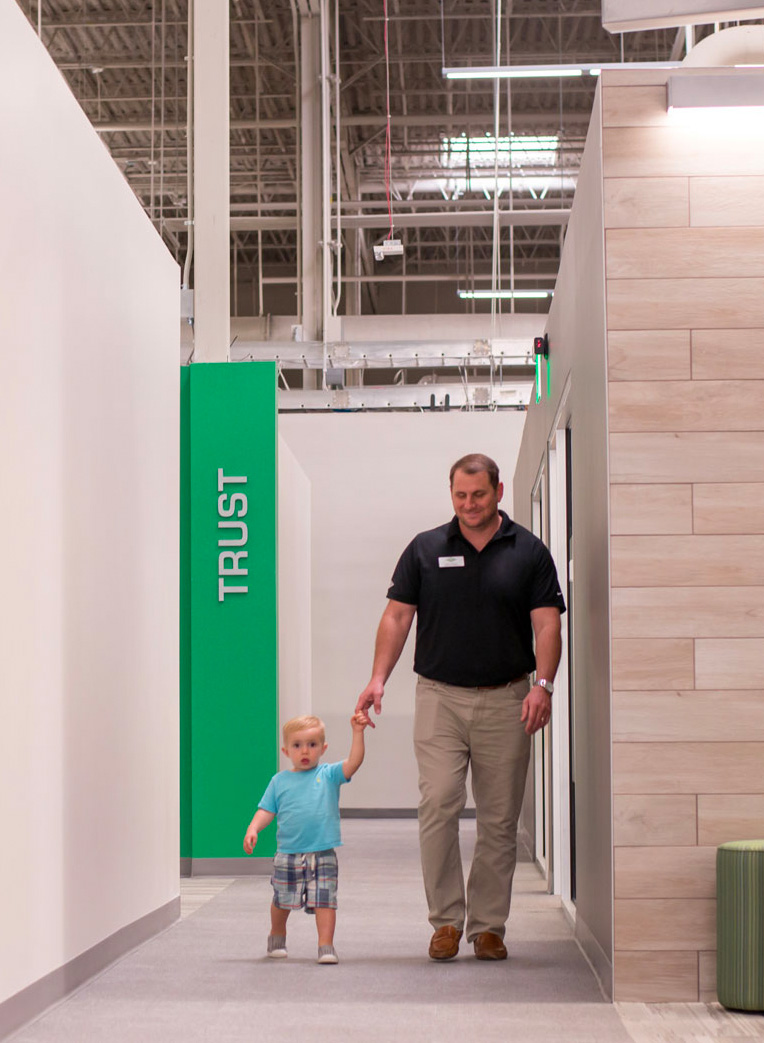 Man walking with young child down a hallway that says trust