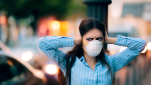 Woman wearing a face mask and covering her ears.