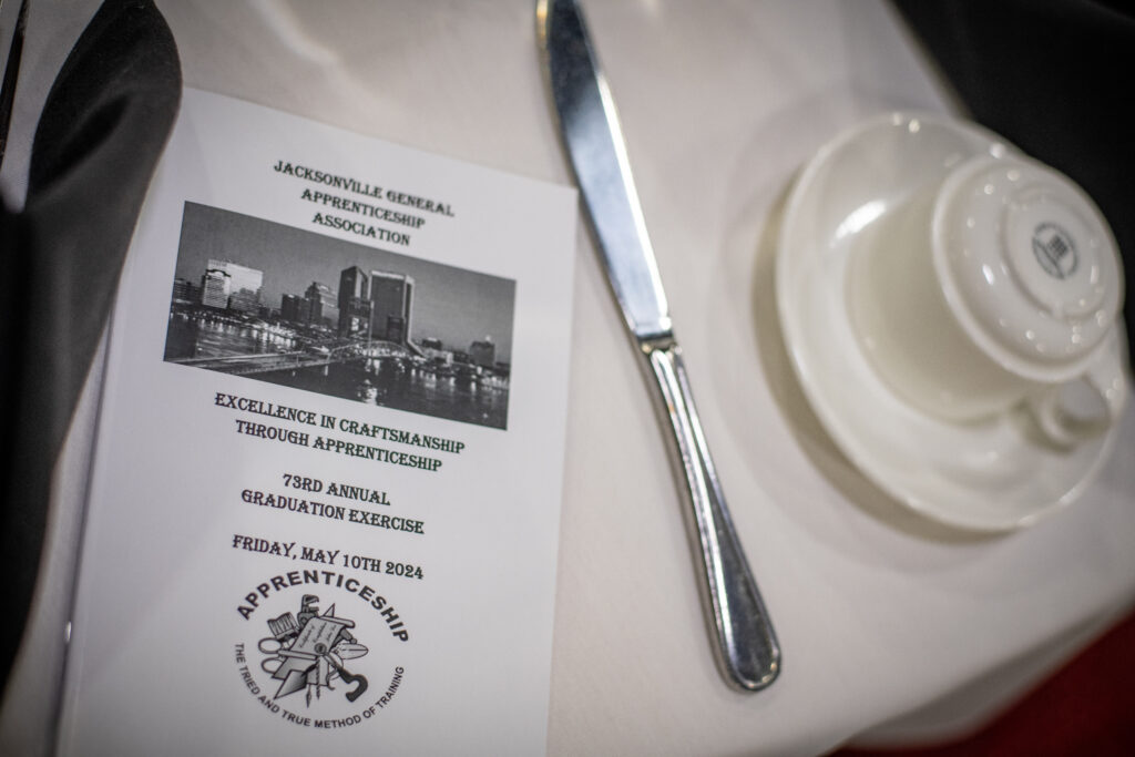 A table with a plate knife on it next to a flyer for the Apprentice Graduation program