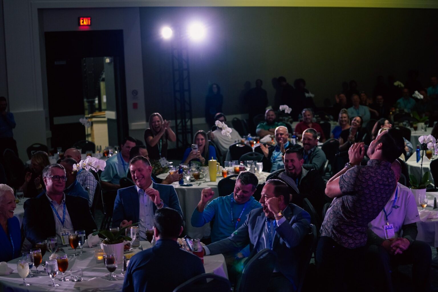 Group of Miller Electric employees cheering and laughing while sitting at banquet tables