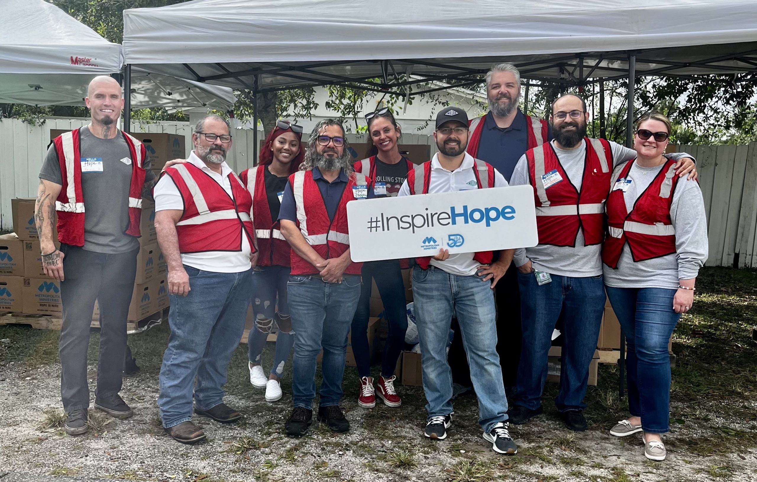 Workers with red vests holding a sign that says Inspire Hope