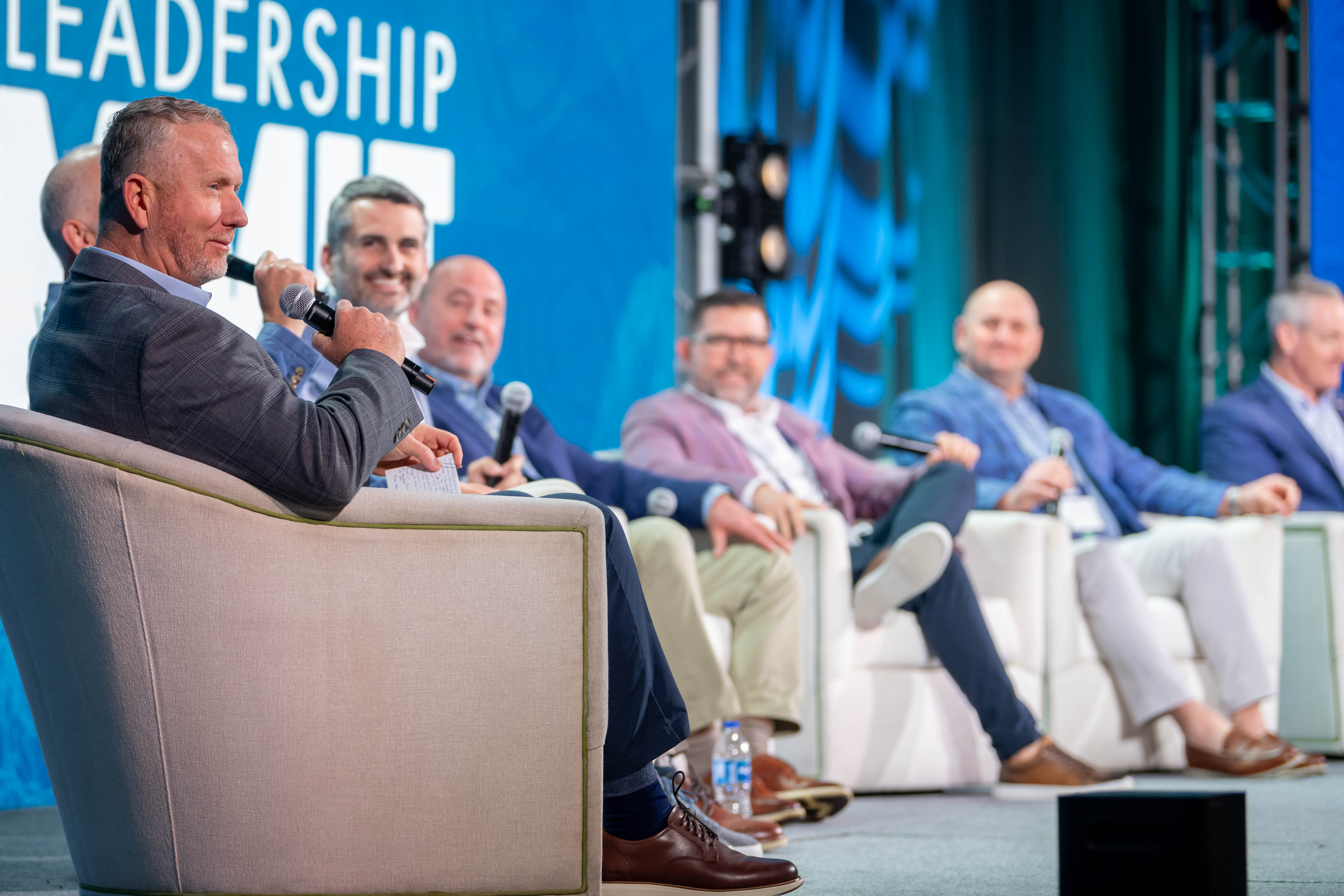 Seated panel of leaders speak into wireless microphone.